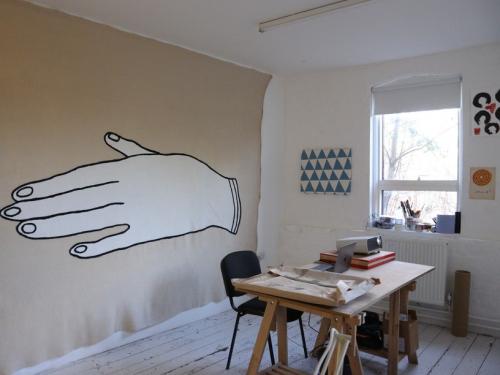 un tavolo, due sedie e una mano disegnata sul muro