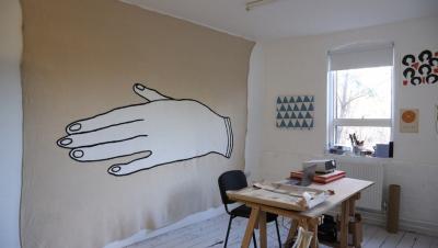 un tavolo, due sedie e una mano disegnata sul muro